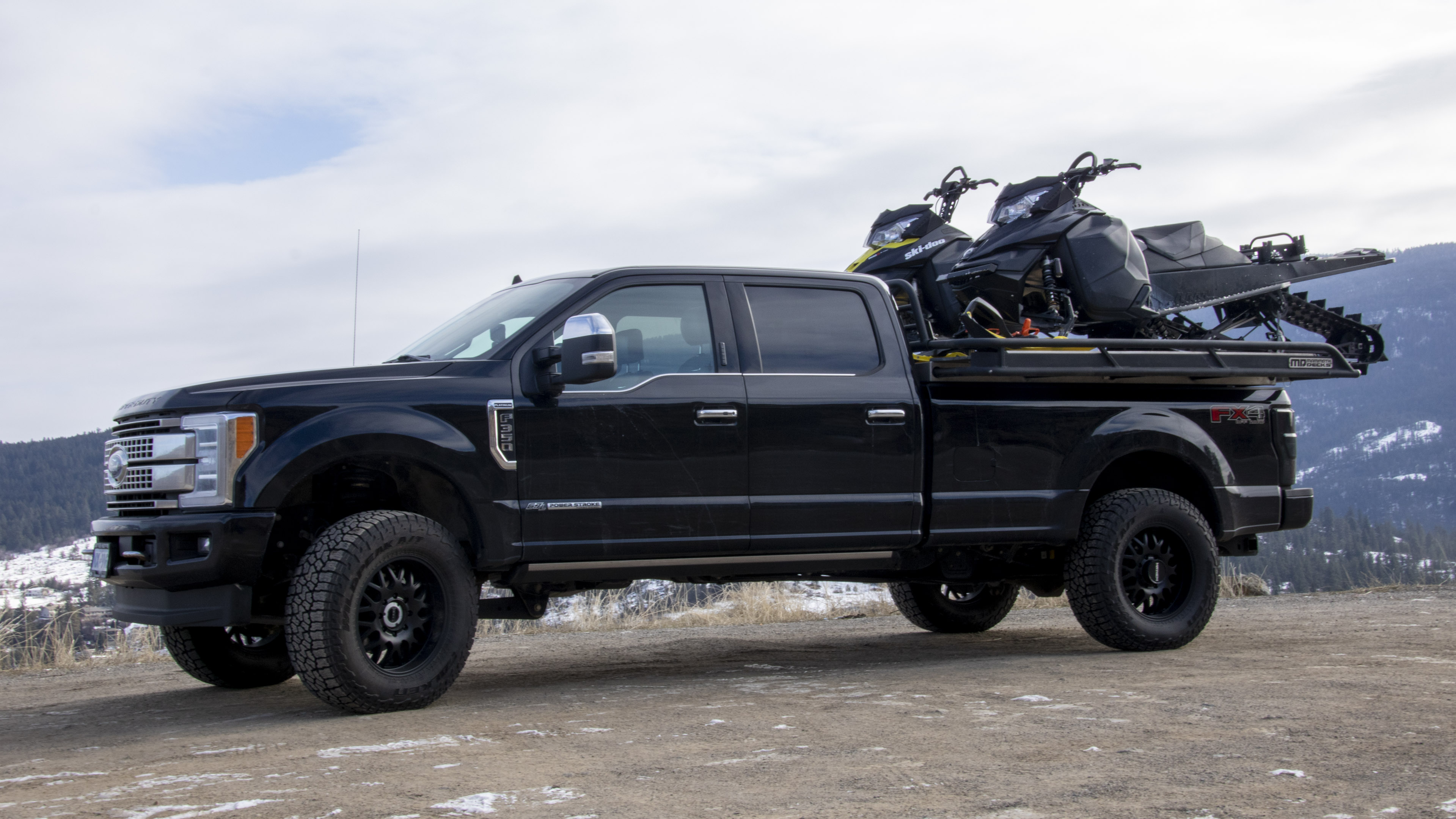 Ford F350 Full Sized Pickup Truck with long bed transporting 2 sleds on the back