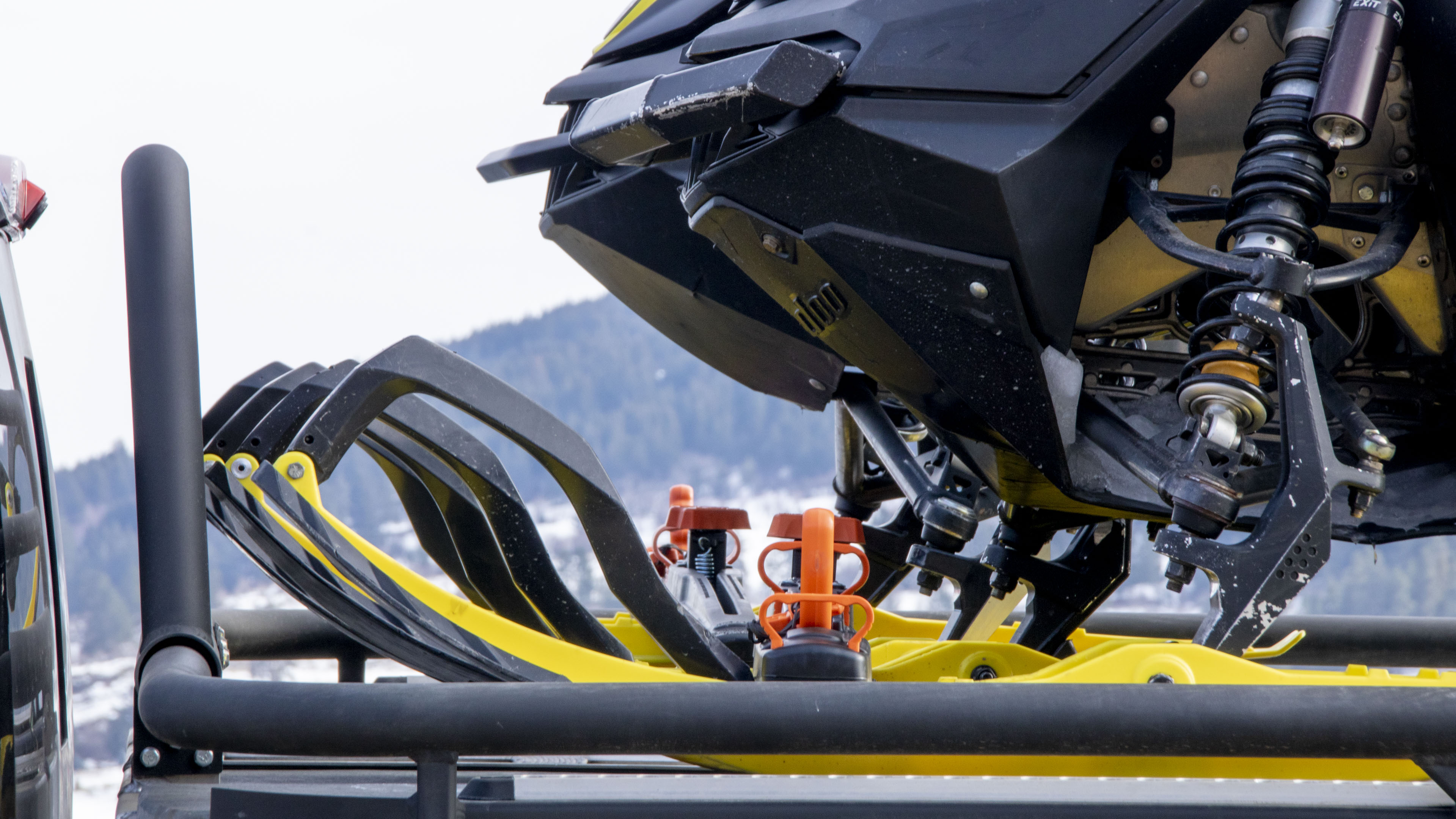 Sled clamp on the snowmobile skis to secure for transport. One of the many options to hold cargo, atvs, sled, and side-by-sides on the deck.
